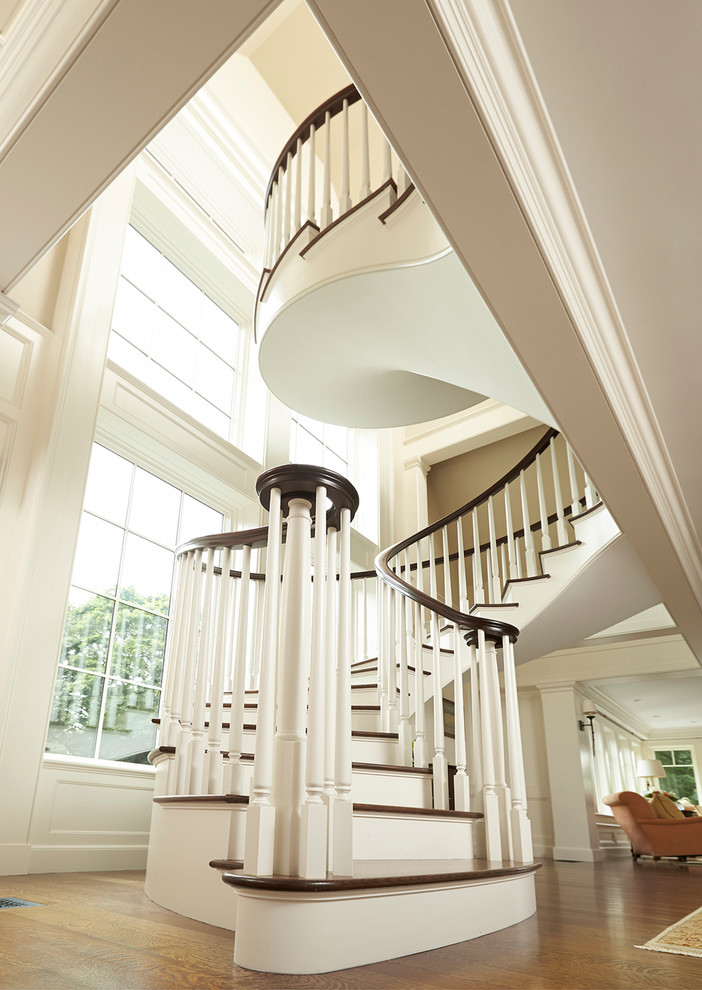 На фото: большая лестница на больцах в классическом стиле с деревянными ступенями и крашенными деревянными подступенками с