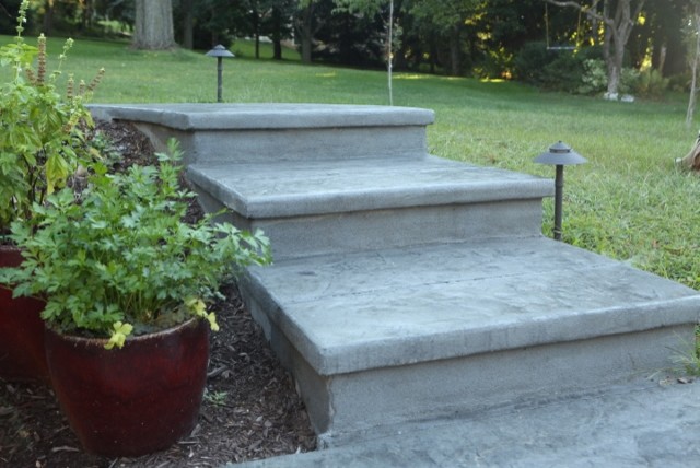 На фото: маленькая изогнутая бетонная лестница в стиле модернизм с бетонными ступенями для на участке и в саду с