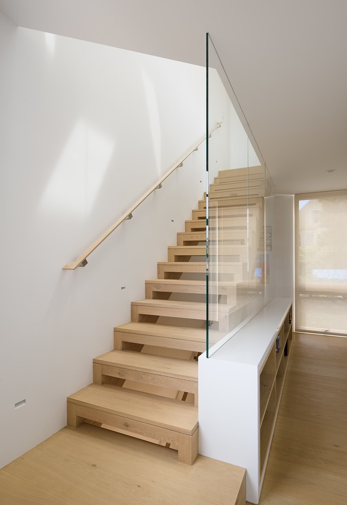 На фото: прямая лестница среднего размера в стиле модернизм с деревянными ступенями и деревянными перилами без подступенок