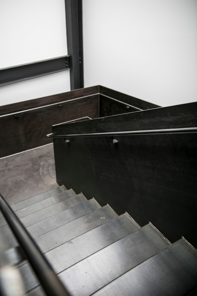 Imagen de escalera en U industrial grande con escalones de metal, contrahuellas de metal y barandilla de metal