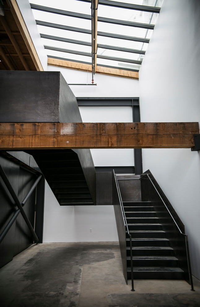 Cette photo montre un grand escalier industriel en U avec des marches en métal, des contremarches en métal et un garde-corps en métal.