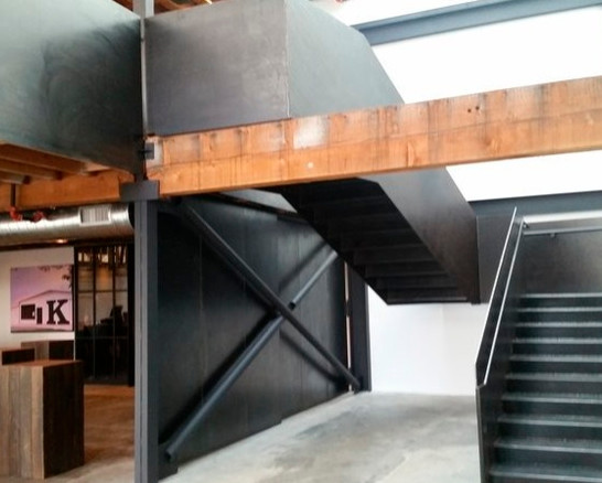 シアトルにある広いインダストリアルスタイルのおしゃれな折り返し階段 (金属の蹴込み板、金属の手すり) の写真