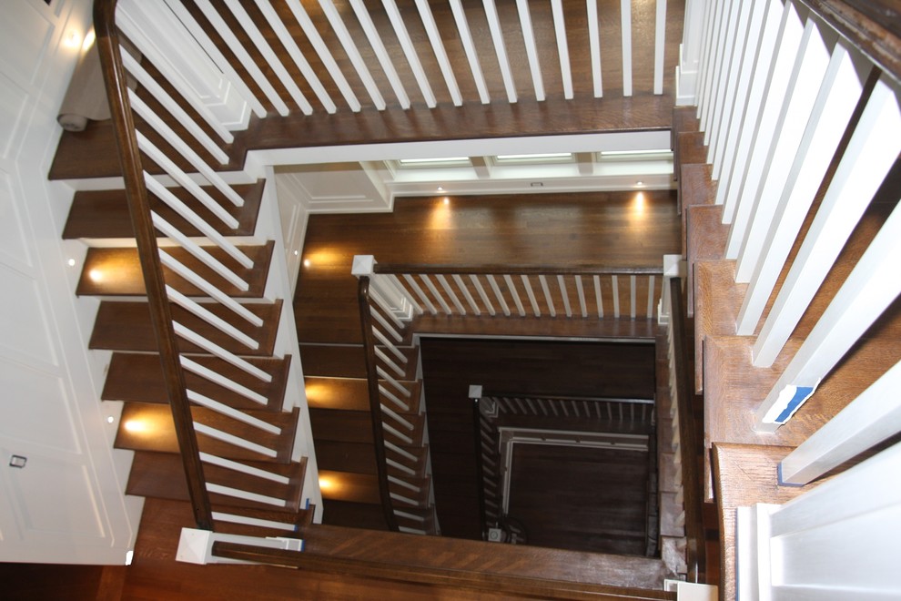Photo of an expansive classic wood u-shaped wood railing staircase in New York with painted wood risers.