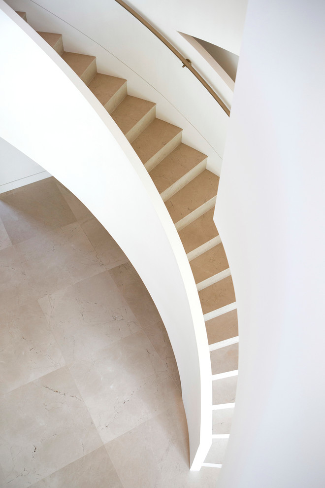 Идея дизайна: большая изогнутая лестница в современном стиле с ступенями из известняка и подступенками из известняка