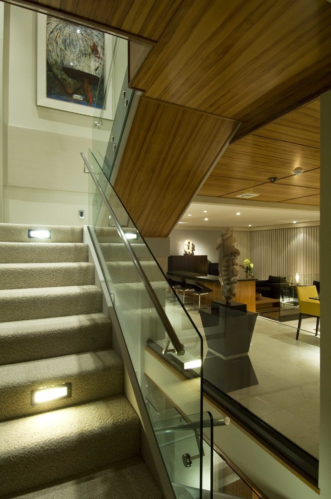 Свежая идея для дизайна: большая п-образная лестница в стиле модернизм с ступенями с ковровым покрытием, ковровыми подступенками и стеклянными перилами - отличное фото интерьера