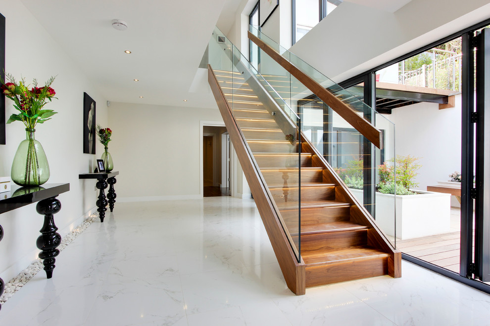 Diseño de escalera recta contemporánea con escalones de madera, contrahuellas de madera y barandilla de vidrio