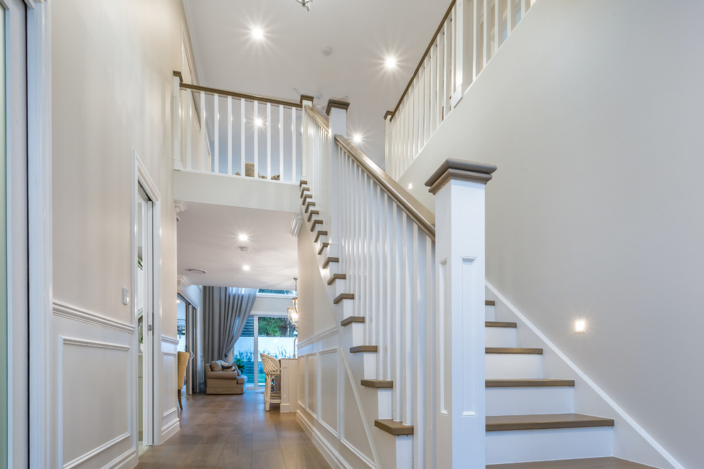 Diseño de escalera recta clásica de tamaño medio con escalones de madera, contrahuellas de travertino y barandilla de madera