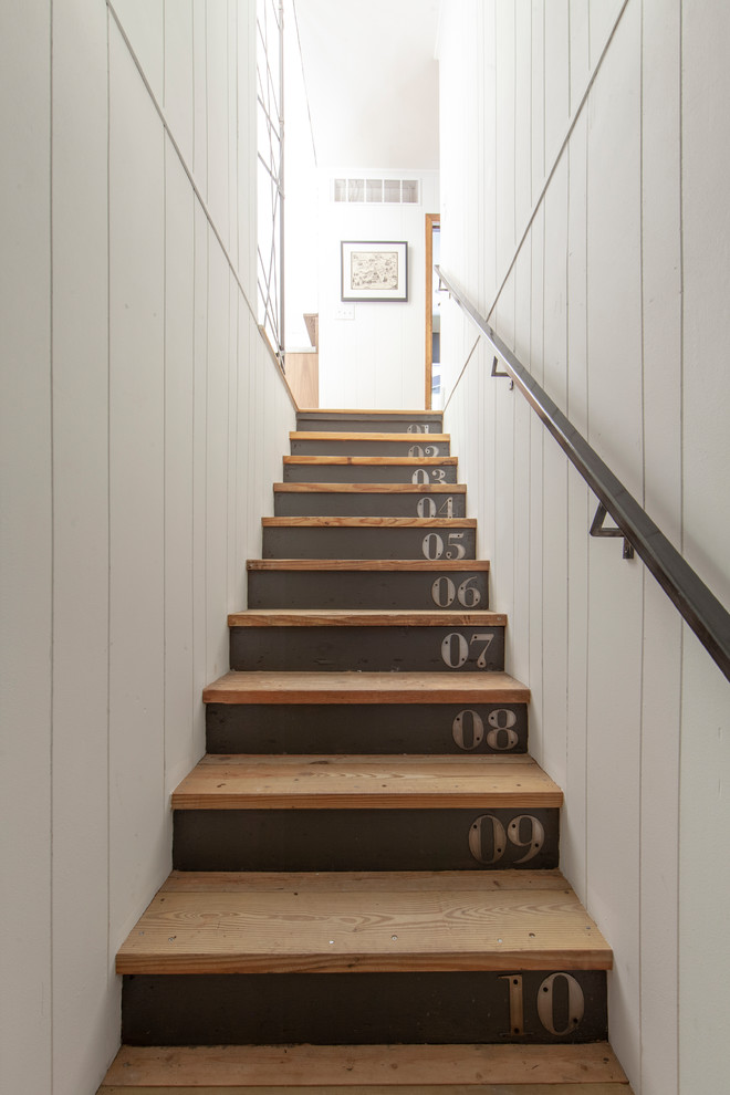 На фото: прямая лестница в стиле кантри с деревянными ступенями и металлическими перилами с