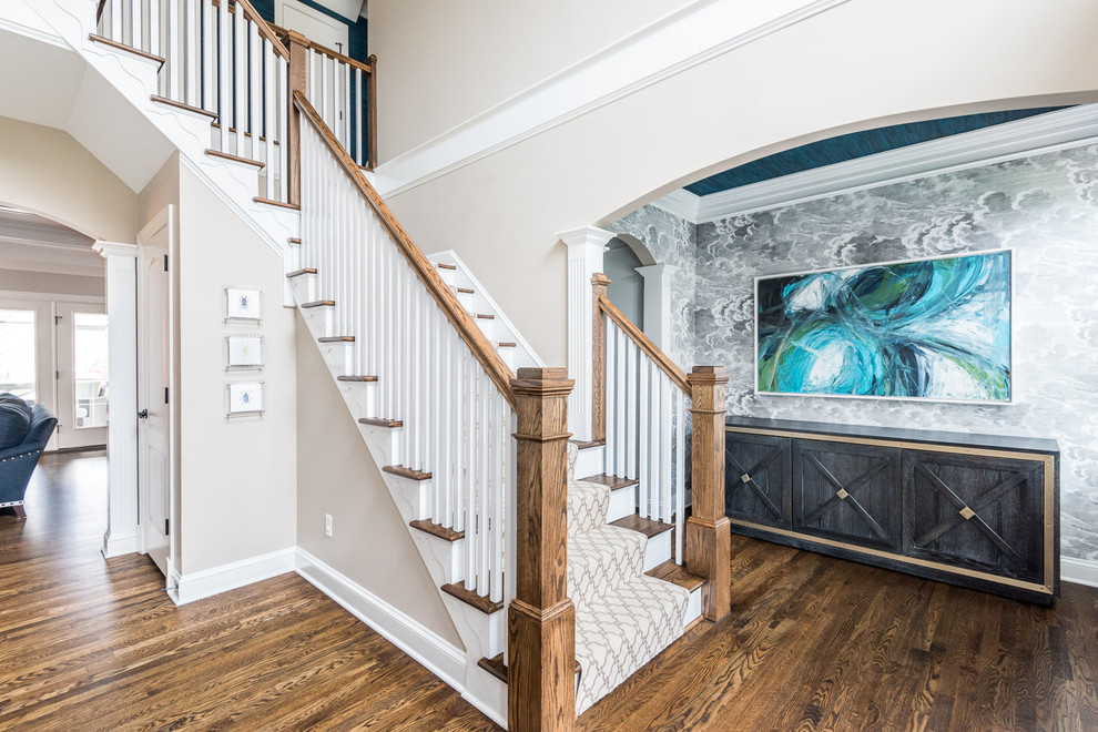На фото: угловая лестница в классическом стиле с ступенями с ковровым покрытием, ковровыми подступенками и деревянными перилами