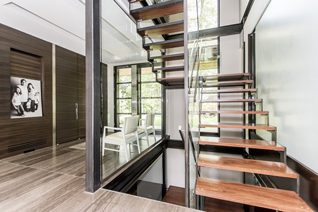 Diseño de escalera en U moderna grande sin contrahuella con escalones de madera y barandilla de vidrio