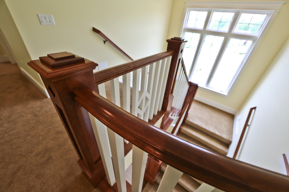 Example of a large classic carpeted u-shaped wood railing staircase design in Grand Rapids with painted risers