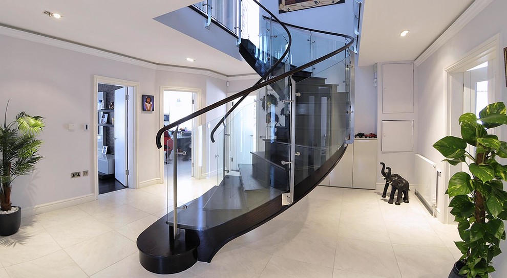 Imagen de escalera curva contemporánea de tamaño medio con escalones de madera pintada, contrahuellas de madera pintada y barandilla de vidrio