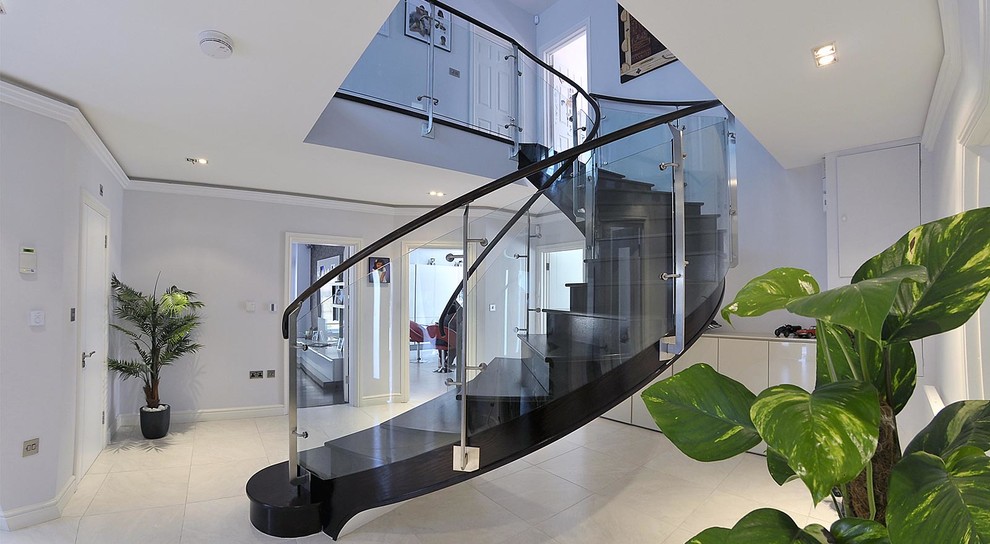 Идея дизайна: изогнутая лестница среднего размера в современном стиле с крашенными деревянными ступенями, крашенными деревянными подступенками и стеклянными перилами