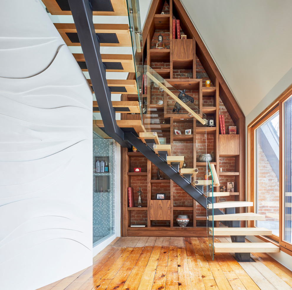 Cette image montre un grand escalier sans contremarche design en U avec des marches en bois et un garde-corps en verre.