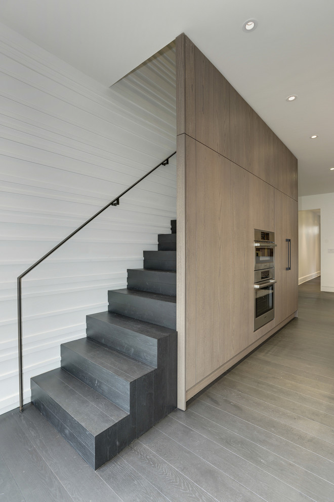 Inspiration pour un escalier droit minimaliste de taille moyenne avec des contremarches en bois, un garde-corps en métal, des marches en bois et éclairage.