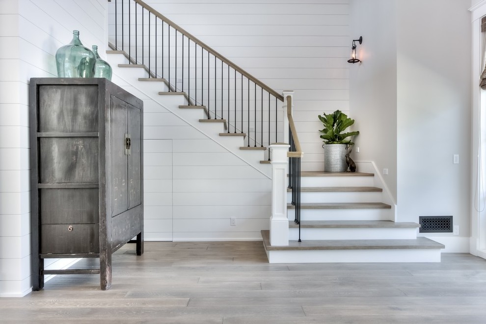 Imagen de escalera en L de estilo de casa de campo de tamaño medio con escalones de madera, contrahuellas de madera pintada y barandilla de varios materiales