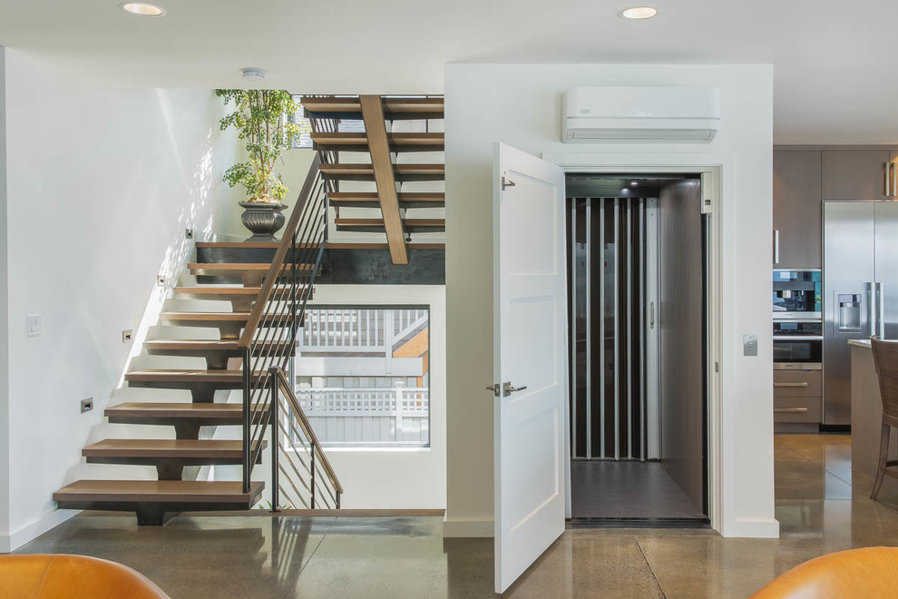 Photo of a medium sized contemporary wood u-shaped metal railing staircase in Seattle with open risers.