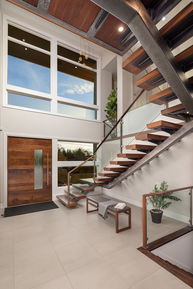 На фото: металлическая лестница на больцах в современном стиле с деревянными ступенями и стеклянными перилами с