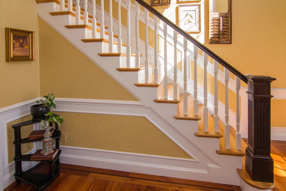 Diseño de escalera en L clásica grande con escalones de madera y contrahuellas de madera pintada