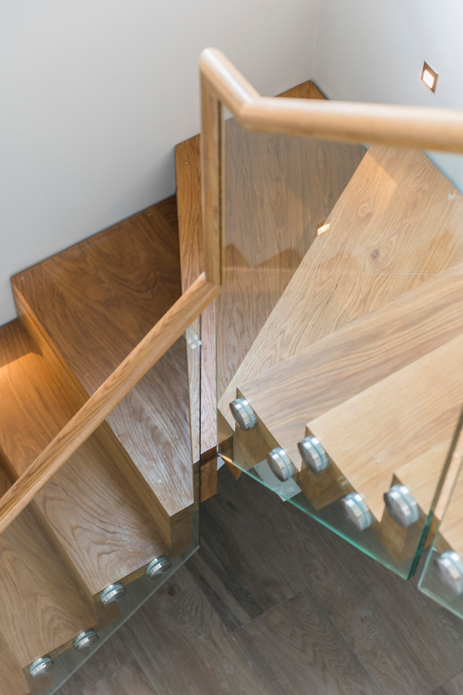 Foto de escalera suspendida actual de tamaño medio con escalones de madera, contrahuellas de madera y barandilla de vidrio