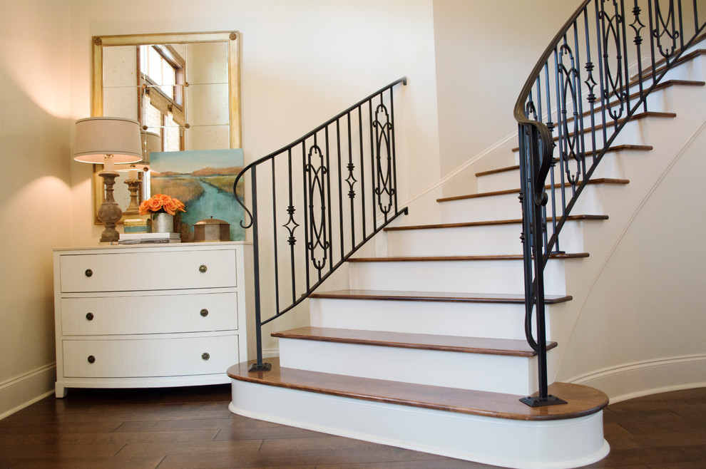 Cette image montre un escalier peint courbe traditionnel de taille moyenne avec des marches en bois, un garde-corps en métal et éclairage.