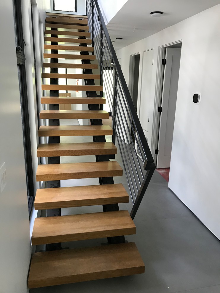 Стильный дизайн: большая лестница на больцах в стиле модернизм с деревянными ступенями и металлическими перилами - последний тренд