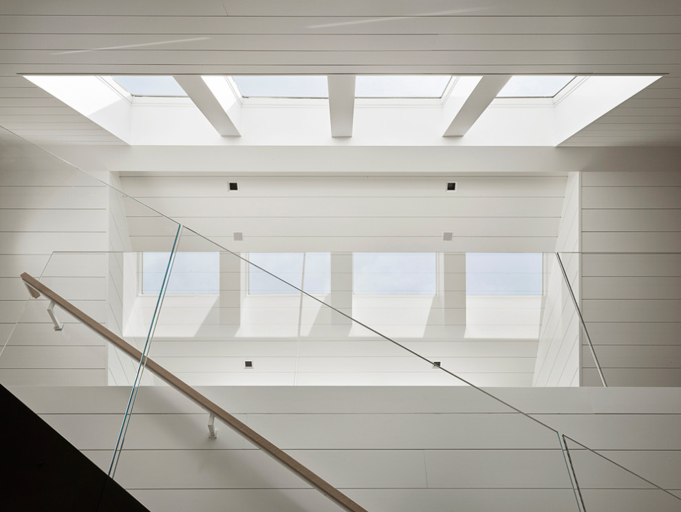 Ejemplo de escalera recta actual grande con barandilla de vidrio