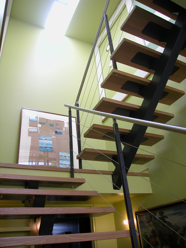 Idée de décoration pour un escalier sans contremarche design en L de taille moyenne avec des marches en bois et un garde-corps en métal.