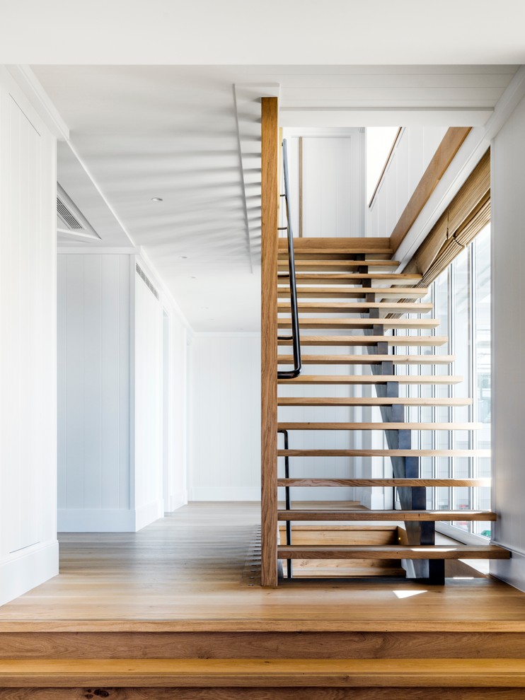 Cette photo montre un très grand escalier sans contremarche droit tendance avec des marches en bois et un garde-corps en métal.