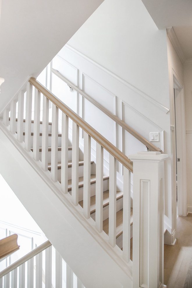 Diseño de escalera en U clásica renovada grande con escalones de madera, contrahuellas de madera pintada y barandilla de madera