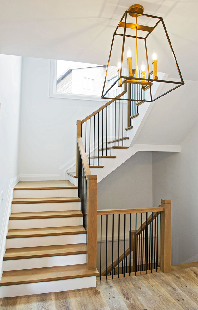 Пример оригинального дизайна: большая п-образная лестница в стиле неоклассика (современная классика) с деревянными ступенями, крашенными деревянными подступенками и перилами из смешанных материалов