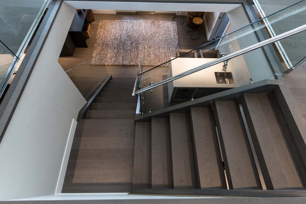 Идея дизайна: большая угловая лестница в современном стиле с деревянными ступенями и стеклянными перилами