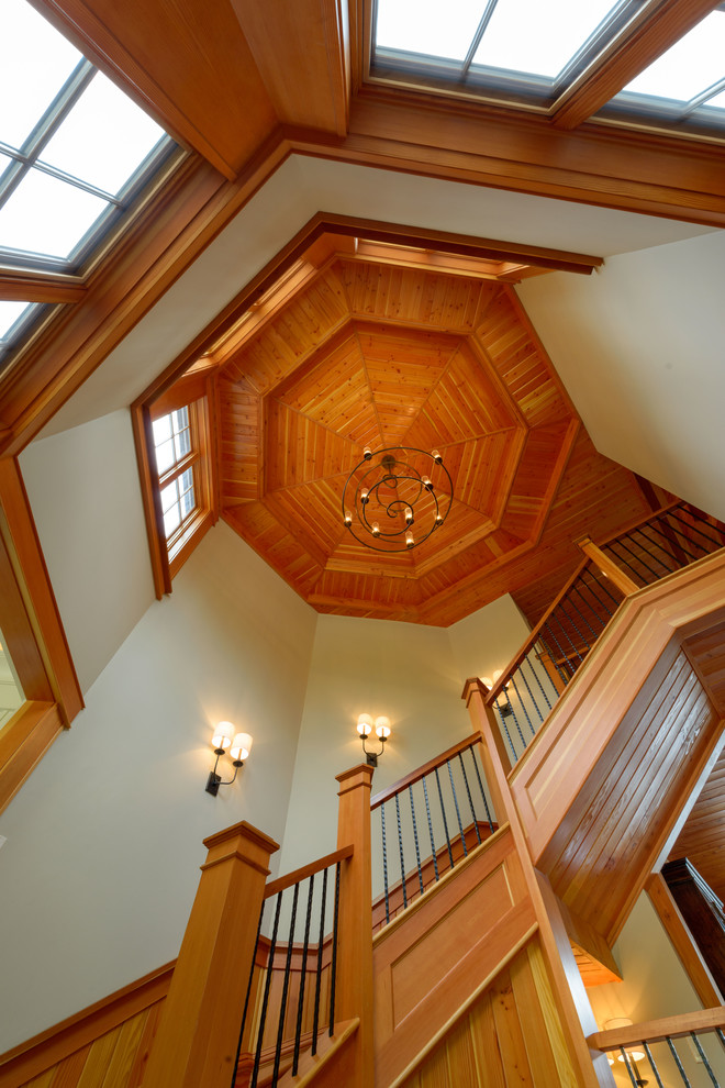Пример оригинального дизайна: большая изогнутая лестница в стиле кантри с деревянными ступенями и металлическими перилами