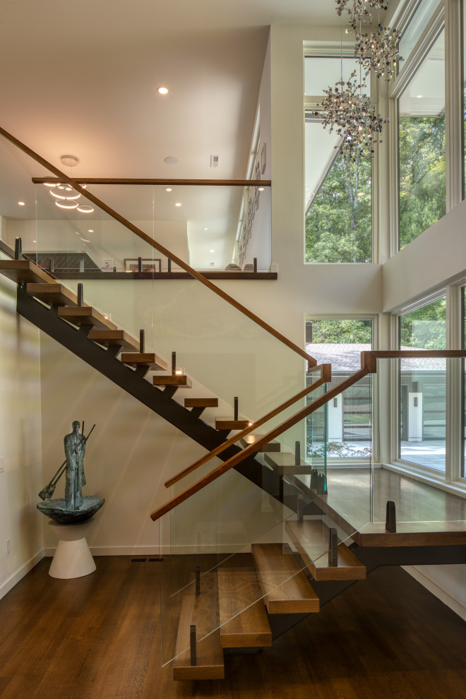 Diseño de escalera suspendida moderna de tamaño medio sin contrahuella con escalones de madera y barandilla de vidrio