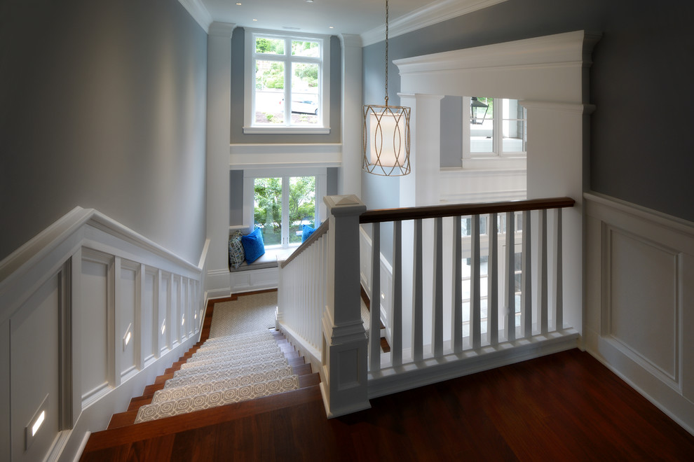 На фото: большая п-образная деревянная лестница в классическом стиле с деревянными ступенями и деревянными перилами