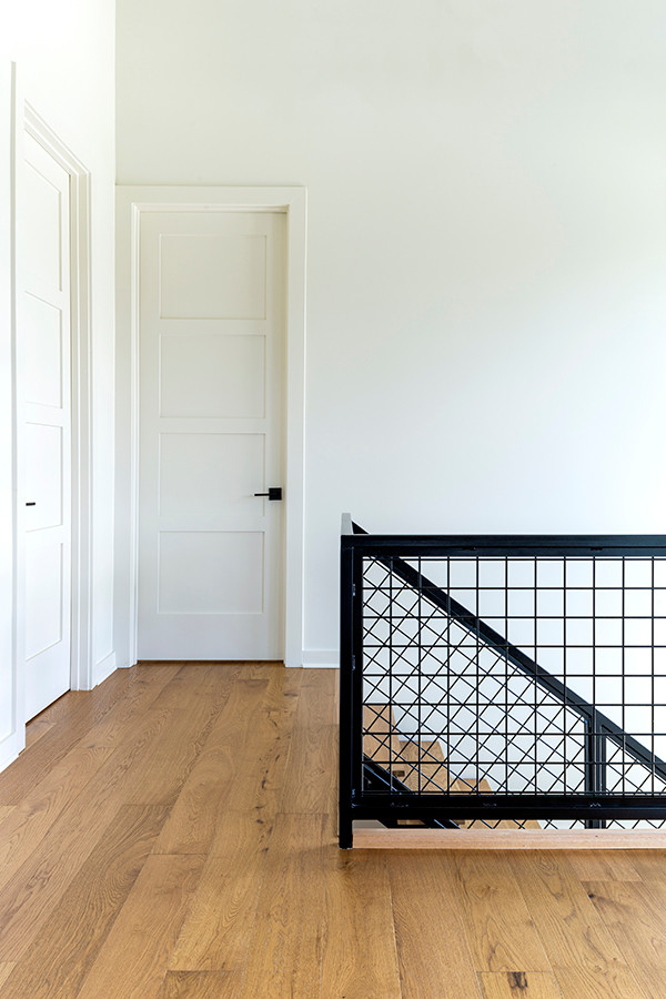 Foto de escalera en U minimalista de tamaño medio con escalones de madera, contrahuellas de metal y barandilla de metal