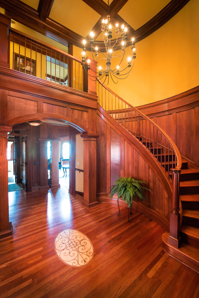 На фото: изогнутая деревянная лестница среднего размера в классическом стиле с деревянными ступенями и деревянными перилами с