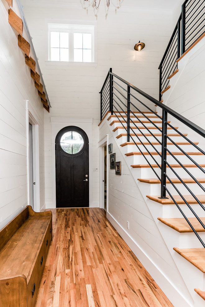 Diseño de escalera en L de estilo de casa de campo de tamaño medio con escalones de madera, contrahuellas de madera pintada y barandilla de metal
