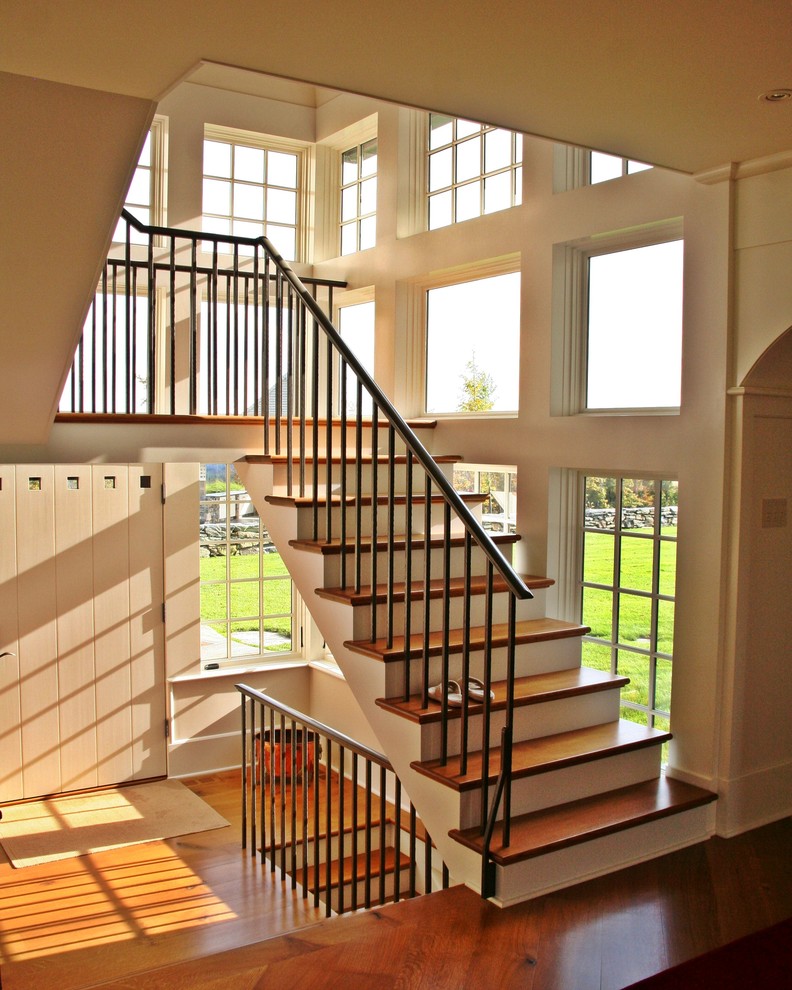 Ejemplo de escalera en U rústica de tamaño medio con escalones de madera, barandilla de metal y contrahuellas de madera pintada