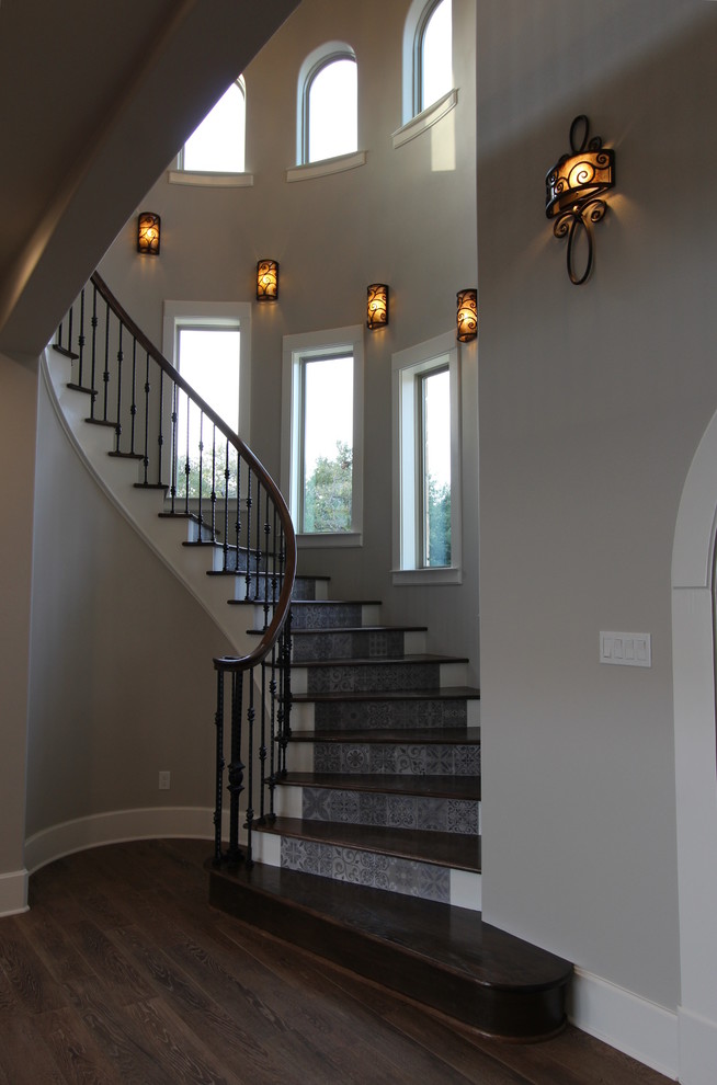 Idée de décoration pour un escalier courbe tradition de taille moyenne avec des marches en bois, des contremarches carrelées et un garde-corps en métal.