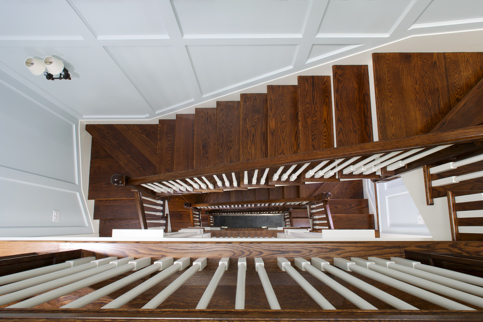 This is an example of a large classic wood u-shaped staircase in Chicago with painted wood risers.