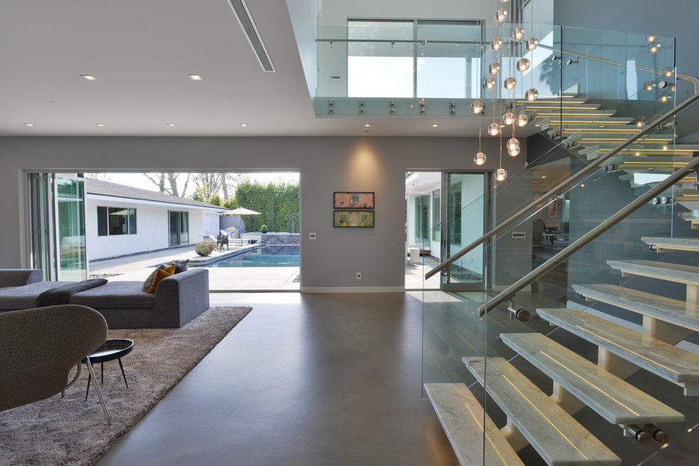 Ejemplo de escalera en L moderna de tamaño medio sin contrahuella con escalones de mármol y barandilla de vidrio