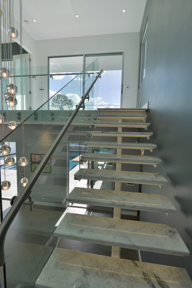 Ejemplo de escalera en L minimalista de tamaño medio sin contrahuella con escalones de mármol y barandilla de vidrio