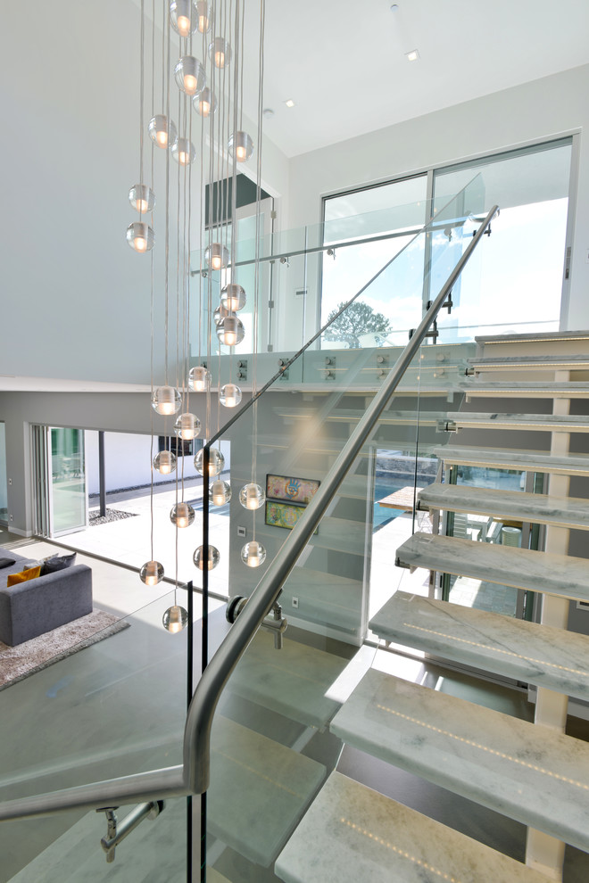 Diseño de escalera en L moderna de tamaño medio sin contrahuella con escalones de mármol y barandilla de vidrio