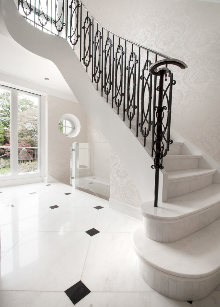 Exempel på en stor klassisk svängd trappa i marmor, med sättsteg i marmor och räcke i metall