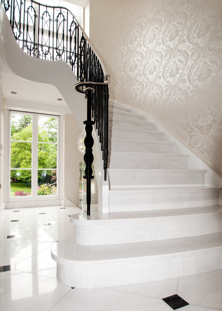 Ejemplo de escalera curva tradicional grande con escalones de mármol, contrahuellas de mármol y barandilla de metal