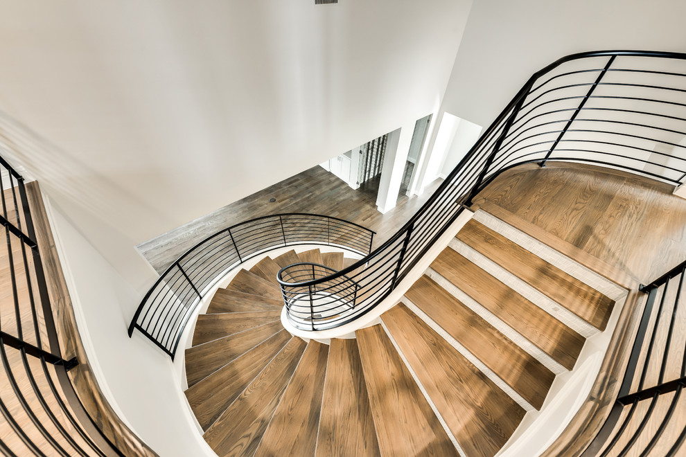 Modelo de escalera curva contemporánea grande con escalones de madera, contrahuellas con baldosas y/o azulejos y barandilla de metal