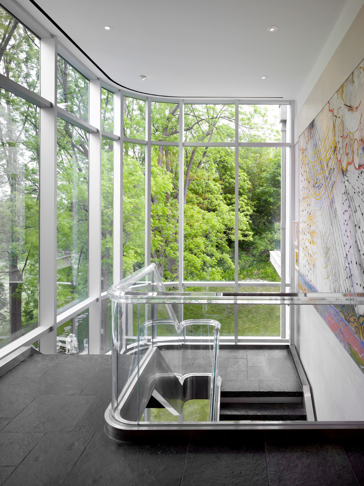 Modern inredning av en stor u-trappa, med klinker och räcke i glas
