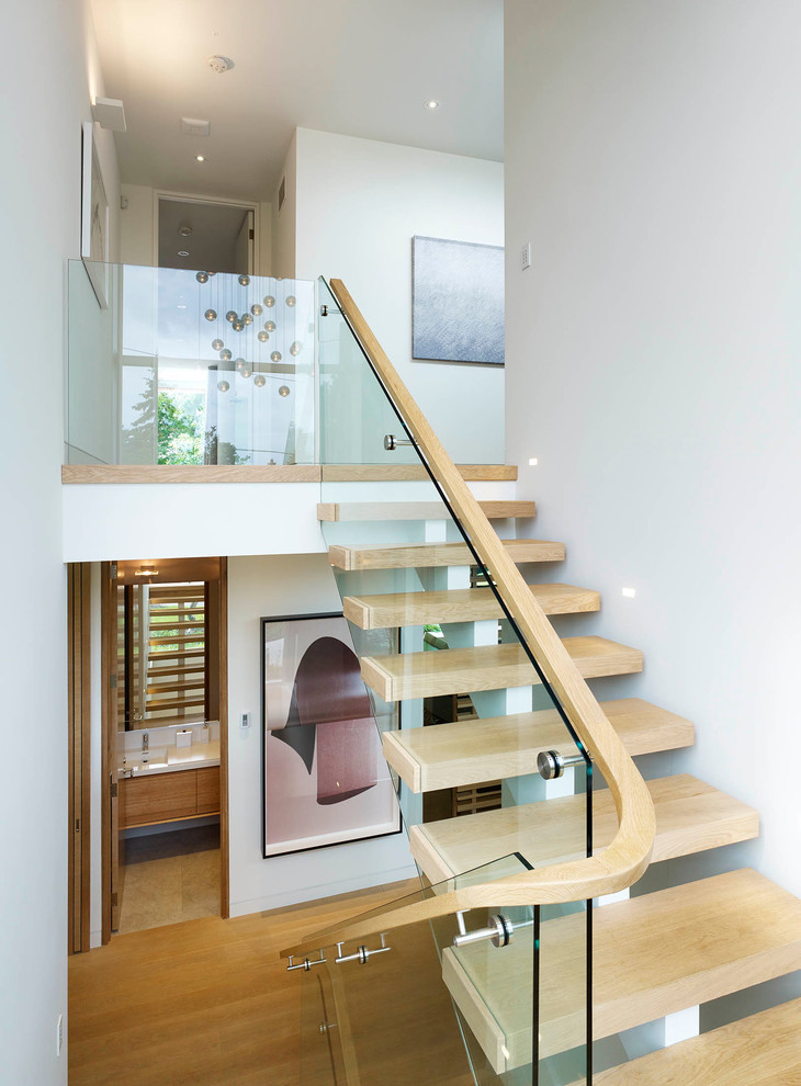 Идея дизайна: большая лестница на больцах в стиле модернизм с деревянными ступенями без подступенок