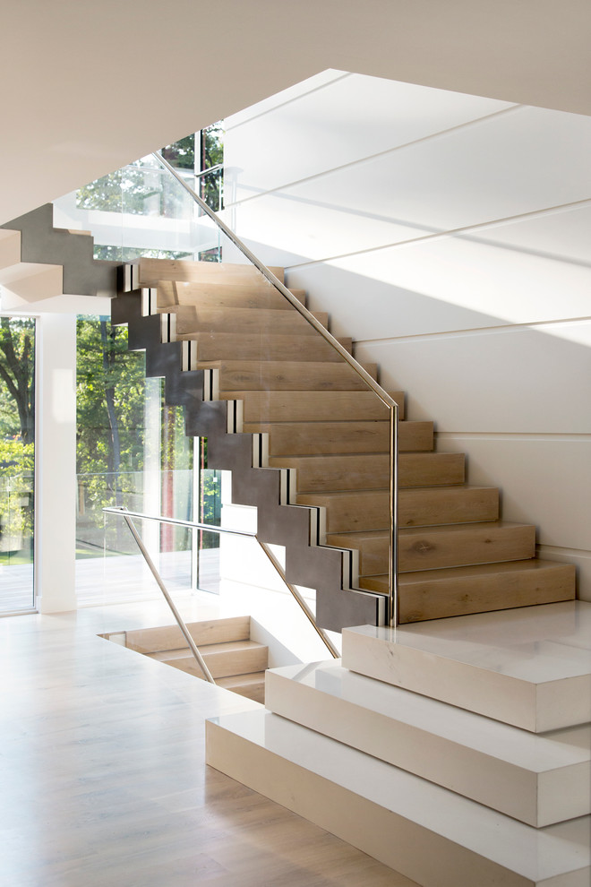Cette image montre un grand escalier flottant minimaliste avec des marches en bois, des contremarches en bois et éclairage.